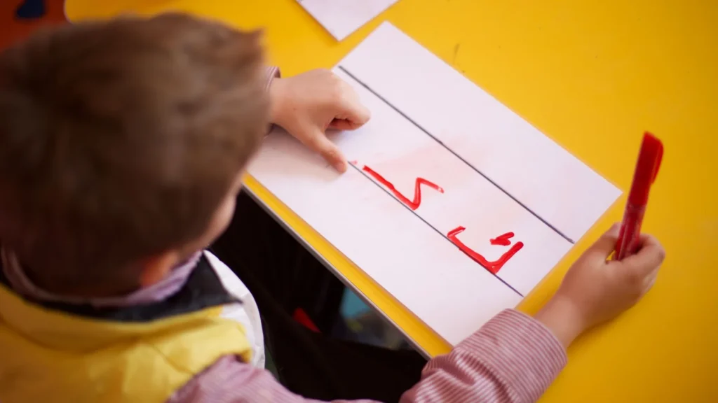 طفل يتدرب على كتابة الحروف العربية في الصف - تعليم اللغة العربية للأطفال في كندا