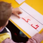 طفل يتدرب على كتابة الحروف العربية في الصف - تعليم اللغة العربية للأطفال في كندا