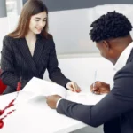 موظفة بنك تساعد عميلاً على توقيع أوراق فتح حساب، مقارنة البنوك الكندية للقادمين الجدد