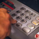 يد تضغط أزرار صراف آلي، في موضوع رسوم البنوك في كندا