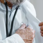 طبيب يرتدي معطفاً أبيض ويمسك سماعة طبية - رخصة مزاولة الطب في كندا
