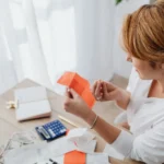 امرأة تراجع إيصالاتها بالآلة الحاسبة استعداداً لاستخدام برامج تقديم الضرائب المجانية في كندا