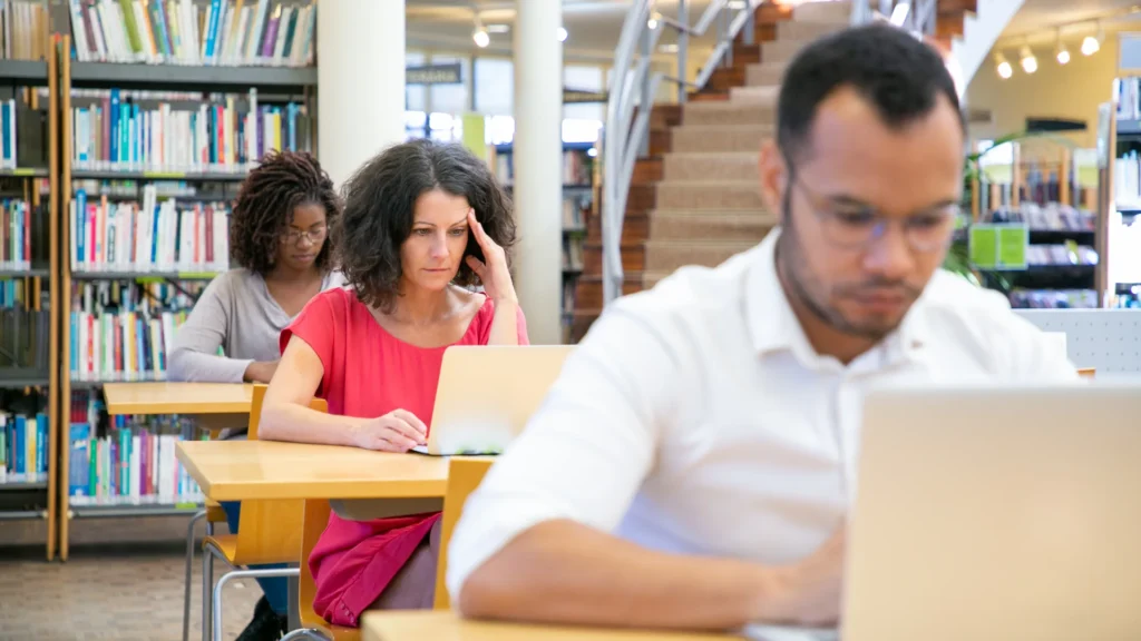 طلاب بالغون يعملون على الحواسيب داخل مكتبة دراسية، الكليات المهنية في أونتاريو وتمويل OSAP