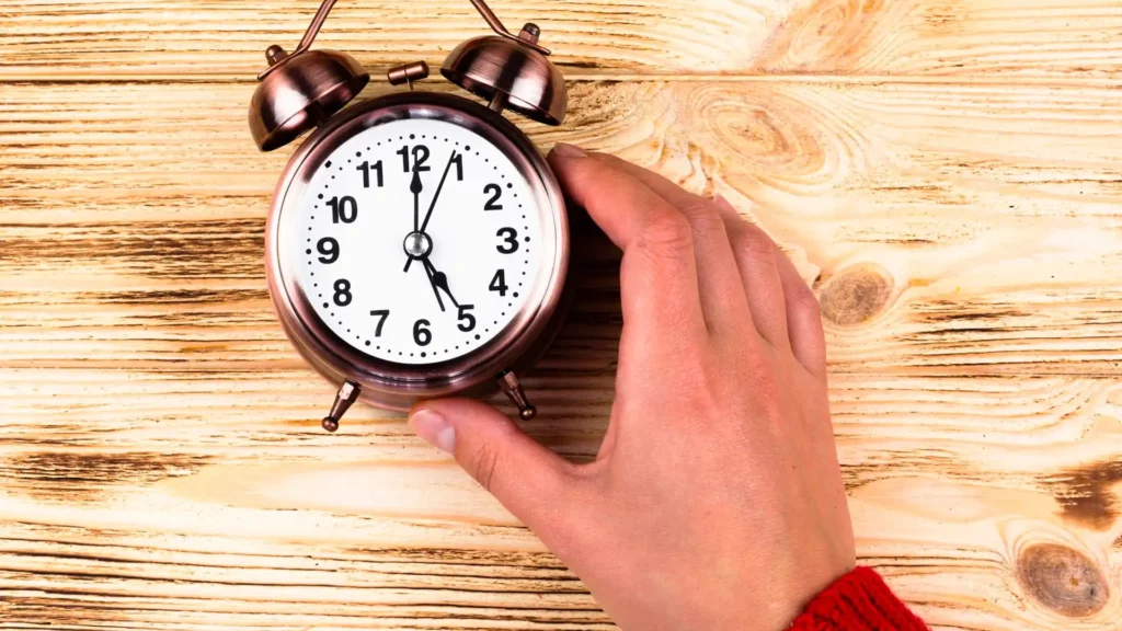 يد تمسك ساعة منبه نحاسية، تغيير الساعة في كيبيك